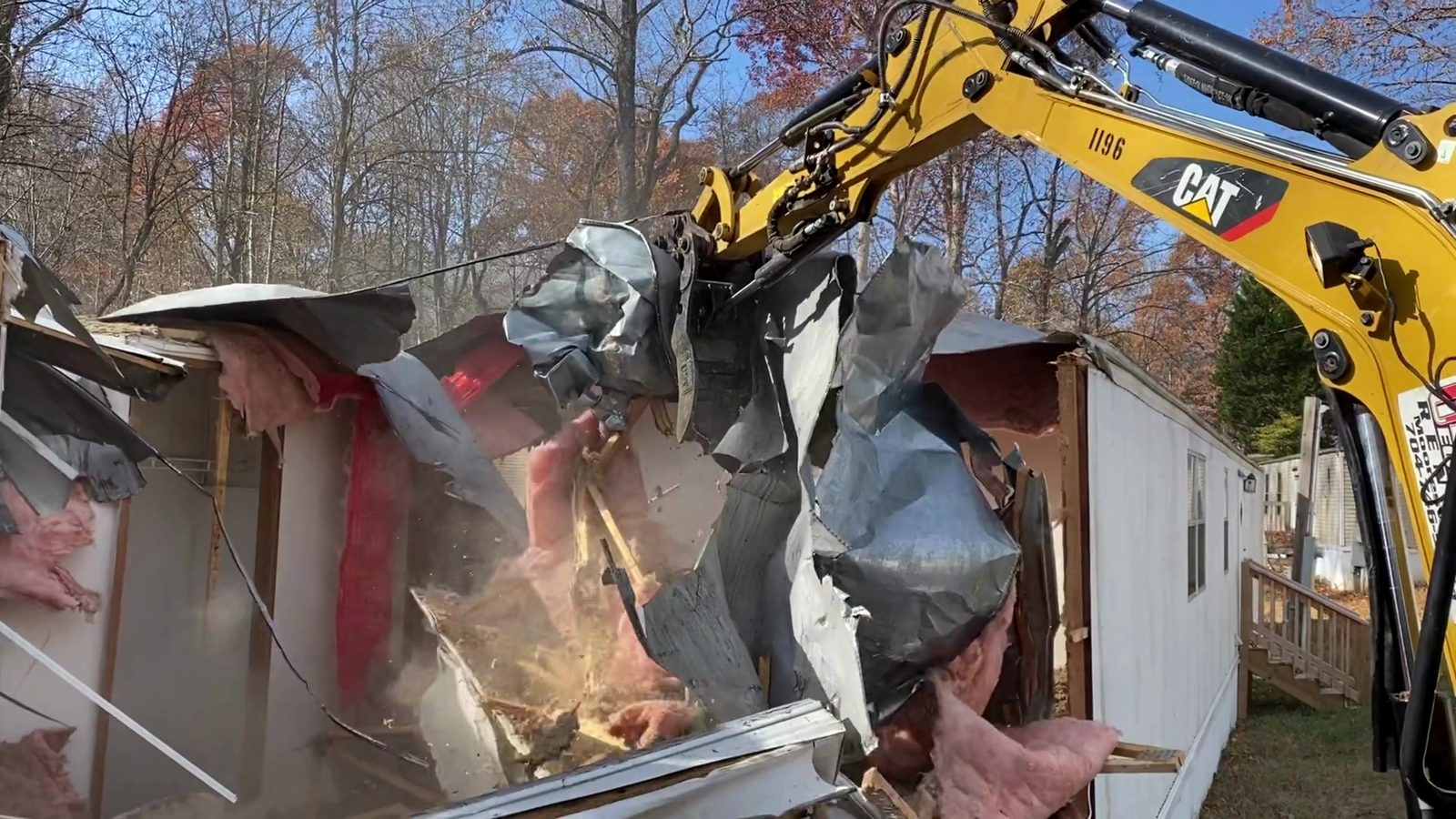 Excavator peeling the metal roof off a mobile home during demolition in Denver NC