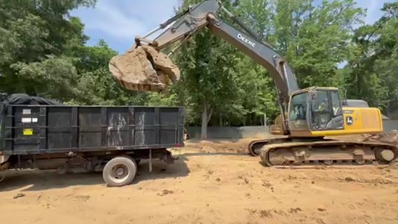 Excavator loading excavated spoil into a Raider Site Services dump truck near Charlotte NC