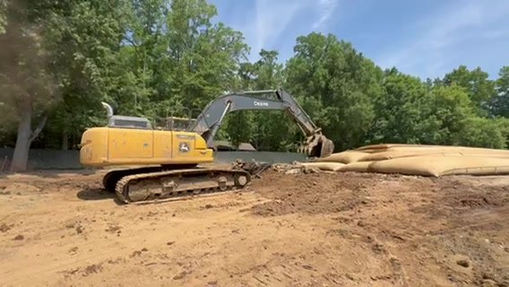 Excavator cutting into a spoil pile during site cleanup near Charlotte NC